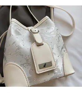 Detailed close-up of a silver jacquard bucket bag with white trim and metal stud accents