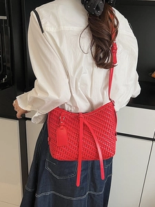 Sac bandoulière rouge tissé pour femme porté par un mannequin dans un décor moderne