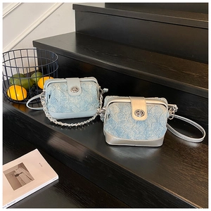 Detailed view of light blue denim quilted crossbody bags with silver hardware and twist lock