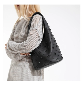 Close-up of black leather tote bag featuring 3D floral appliqués and punk style studs