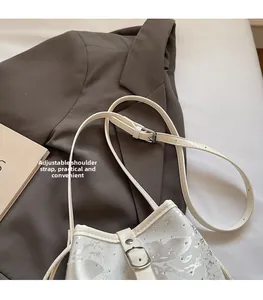 Detail view of white floral bucket bag with adjustable leather strap and silver sequins