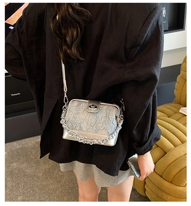 Detail view of silver and blue quilted crossbody bag with metal chain and turn-lock closure