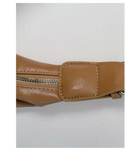 Détail de sac en cuir marron montrant les doubles coutures et la fermeture éclair en métal