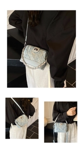 Detail view of light blue quilted crossbody bag with silver chain and metal twist lock