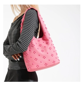 Detailed view of pink leather shoulder bag featuring 3D floral accents and metal rivets