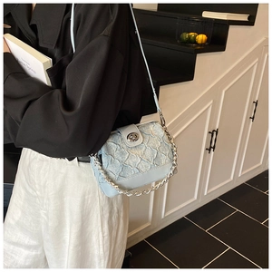 Detail of light blue crossbody bag with quilted pleat texture and silver chain strap