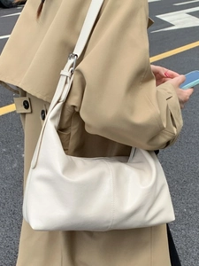 Sac hobo rétro en cuir crème avec bandoulière réglable porté par un mannequin en rue