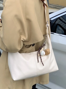 Sac cabas minimaliste en similicuir beige avec breloque de baseball sur la bandoulière