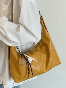 Sac hobo rétro jaune gingembre avec charm de baseball porté par un modèle