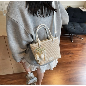 Detail of straw woven bucket bag with pearl tulip charms and leather strap