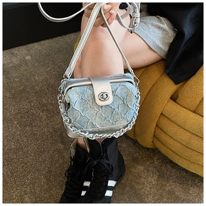 Detailed view of quilted denim box bag with silver metal frame and chain strap