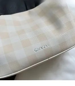 Detailed view of beige checkered fabric with premium silver embroidery branding