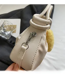 Detail of off-white pleated handbag with silver hardware and yellow plush charm