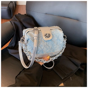 Detailed view of blue denim doctor bag with pleated texture and silver chain strap