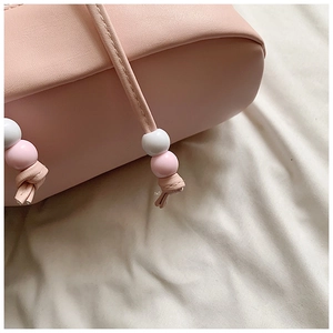 Detail of pink PU leather drawstring bag featuring cute pink and white bead accents