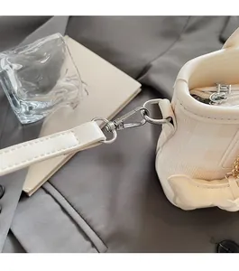 Dettaglio dell'hardware argento e del fiocco sulla borsa a secchiello beige a scacchi