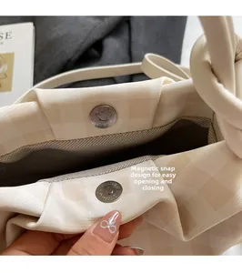 Detail view of the beige checkered handbag showing its magnetic clasp and lining