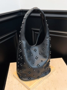 Sac hobo en cuir noir avec clous pour femme présenté sur un support en marbre chic