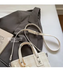 Dettaglio della borsa tote a scacchi color crema con tracolla regolabile e catena in metallo
