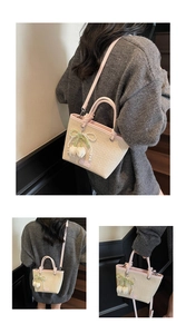 Detail of straw tote bag with pink leather trim, pearl charm, and tulip decoration
