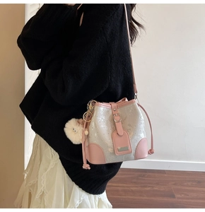 Detail of pink and pearl white bucket bag with glitter finish and plush pompom