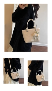 Detail of woven bucket bag with leather strap and pearl flower charm accessory