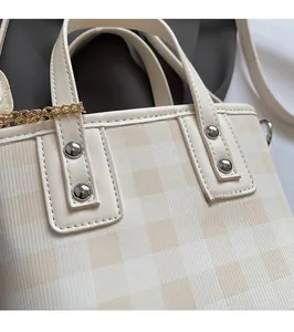 Dettaglio borsa a scacchi beige con rivetti in argento e cuciture di alta qualità