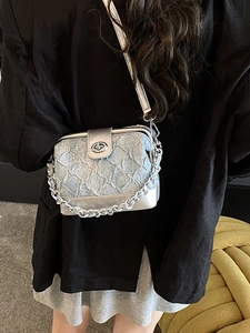 Quilted denim and silver crossbody box bag with chain strap worn by a model