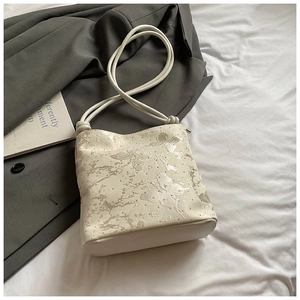 Détail du sac crème avec imprimé papillon marbré et rivets argentés élégants