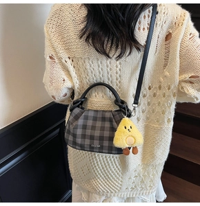 Grey plaid handbag with black leather handle and yellow plush charm on model