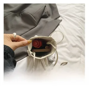 Detail view showing interior capacity of a white drawstring mini bag with daily cosmetics