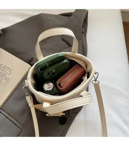 Vista dall'alto della borsa a secchiello trapuntata beige con spazio per telefono e portafoglio
