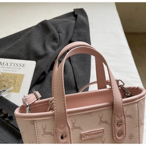 Close-up of pink leather tote bag with deer print, silver hardware, and fine stitching details