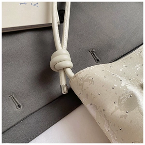 Détail du sac à texture satinée avec pois pailletés et finitions de bandoulière nouée