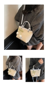 Close-up of woven straw tote bag with light blue leather handles and tulip charms