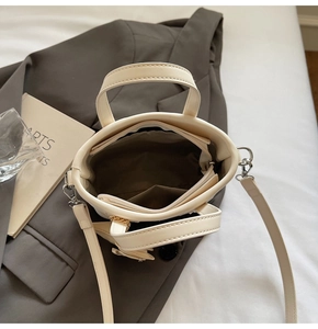 Top view of cream bucket bag showing inner lining, zipper pocket, and silver hardware