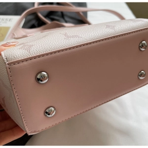 Close-up of pink bucket bag bottom with protective silver metal feet and embossed leather