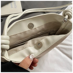Détail du sac en cuir blanc avec fermeture magnétique et doublure en tissu chevron