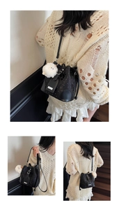 Detail of black drawstring bucket bag with sequins and a white fluffy pompom charm
