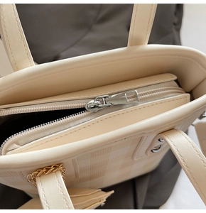 Detail of cream plaid tote bag showing smooth silver zipper and golden chain handle