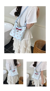 Detail of light blue bow tote bag with red heart charm and ribbon print design