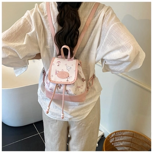 Mini pink backpack with cartoon print shown on model's back for size reference