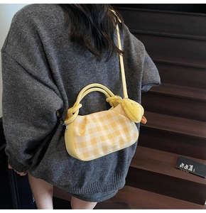 Yellow checkered crossbody bag featuring a plush duck pendant shown on a model
