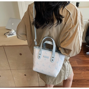 Detail of blue and white deer print crossbody bag worn by model in a cozy indoor setting