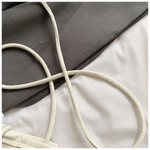 Detail of cream faux leather shoulder strap with visible stitching on a crossbody bag