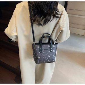 Detail showing printed deer pattern and star motifs on small dark grey bucket bag