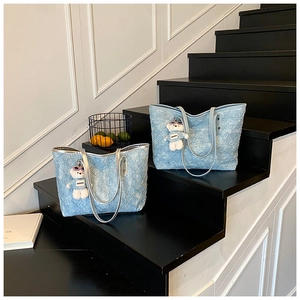 Detail of woven light blue tote bag with quilted texture and cute white bear charm