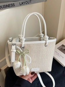 Minimalist beige woven bucket bag with white faux leather handles and tulip pearl charm