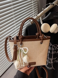 Straw tote bag with brown leather handles and a pearl tulip charm for summer style