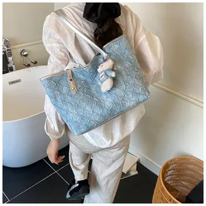 Close-up of light blue pleated tote bag with silver straps and cute plush bear charm